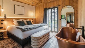 A wooden interior with a bed, a large window, and a copper bathtub. - L'Écrin  (Megève)