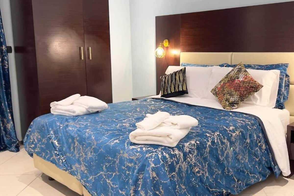 A hotel room with a bed, a wardrobe, and a nightstand.