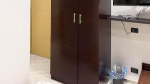 Une pièce avec une armoire en bois foncé, un téléviseur fixé au mur et un appareil de climatisation.