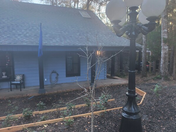 Una casa con fachada azul, un jardín con bancales elevados y una farola.
