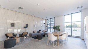 A modern living room with a sofa set, a dining table, and a large window offering a view of the outside.