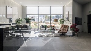 A modern interior with a reception desk, seating area, and large windows offering a view of the cityscape.