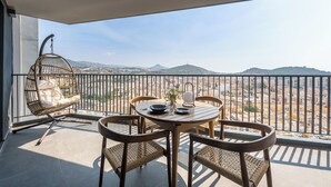 A balcony with a round table, four wicker chairs, and a hanging chair with cushions.