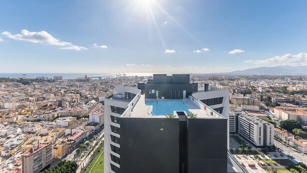 A high-rise building with a rooftop pool, offering a panoramic city view.