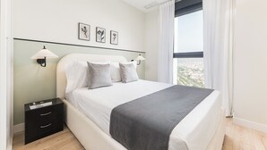 A modern bedroom with a bed, bedside tables, and a window with curtains.
