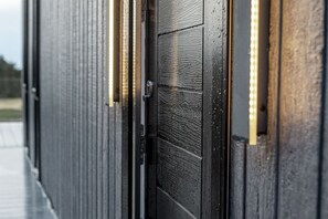 Un gros plan d’une porte en bois sombre, dont la surface est texturée et qui est dotée d’une poignée métallique.