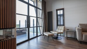 Ein modernes Wohnzimmer mit einem großen Schiebeglastür, einem Ledersessel, einem Sofa und einem kleinen Beistelltisch.