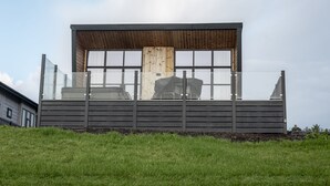 Ein modernes Gebäude mit Holzfassade, großen Fenstern und einem Balkon.