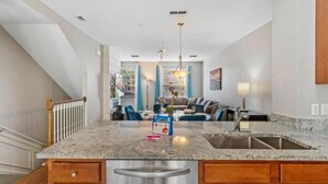 A modern kitchen with a granite countertop, stainless steel sink, and wooden cabinets.