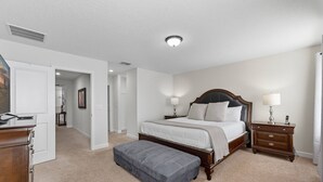 A bedroom with a bed, nightstands, a dresser, and an ottoman.