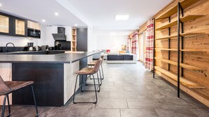 A modern kitchen with a central island, bar stools, and a wooden wall. - Chalet 'Salt Lake' with Mountain View, Private Terrace and Wi-Fi (Fontcouverte-la-Toussuire)