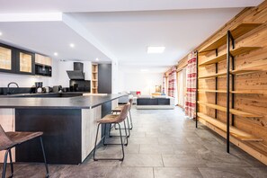 Une cuisine moderne avec un îlot central, des tabourets de bar et un mur en bois.