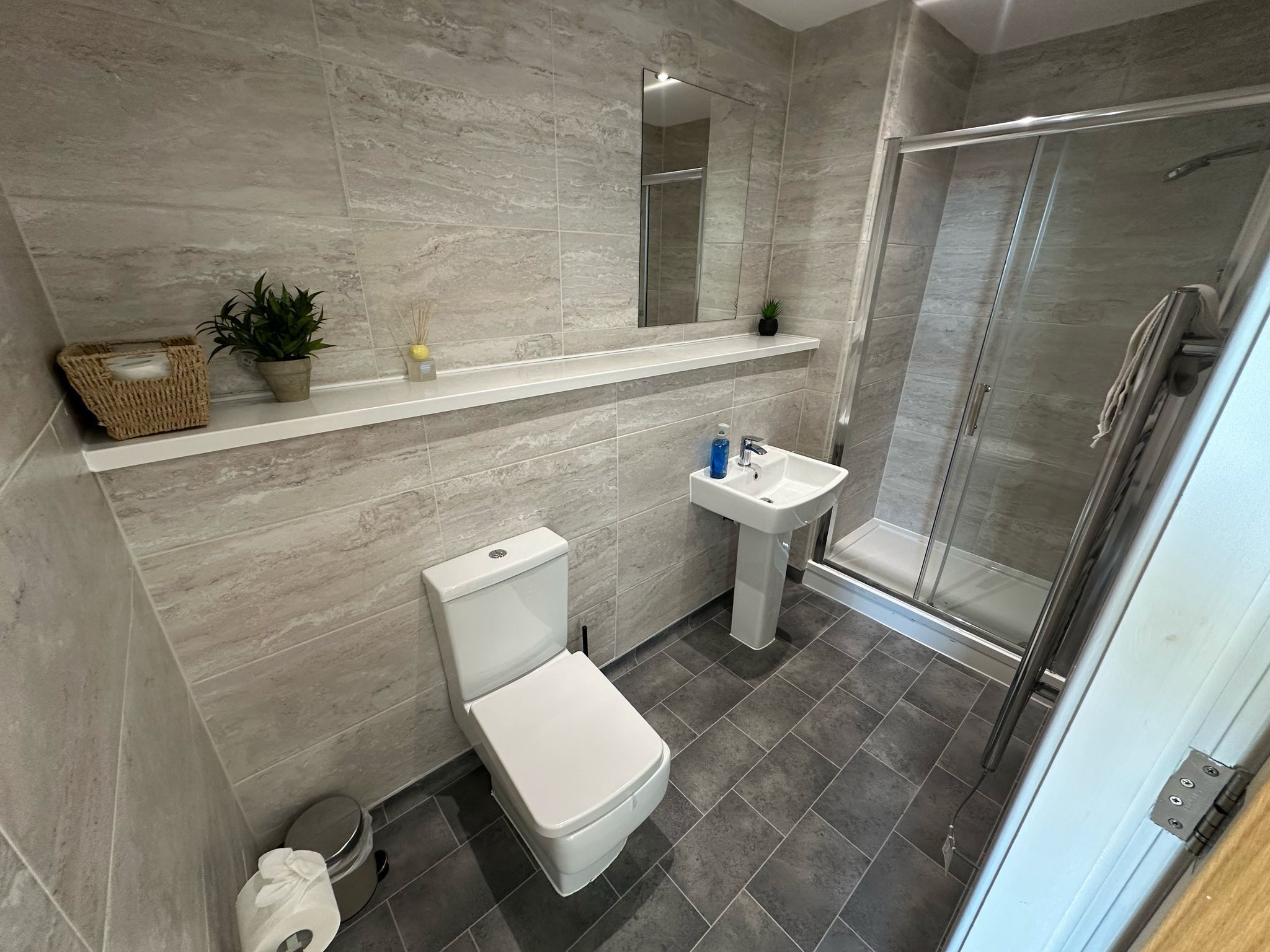 Een moderne badkamer met toilet, wastafel en douche.