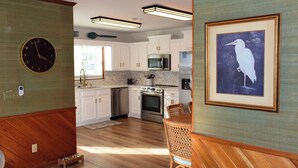 Una cocina moderna con armarios blancos, electrodomésticos de acero inoxidable y una zona de comedor de madera.