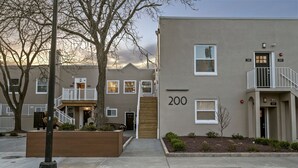 Un edificio residencial de varios pisos con fachada plana, unidades numeradas y un pequeño balcón en el nivel superior.