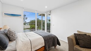 Ein Schlafzimmer mit einem Bett, einem Sessel, einem Fenster und einem Bild an der Wand.