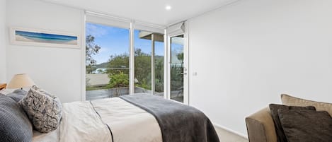 A bedroom with a bed, a chair, a window, and a picture on the wall.