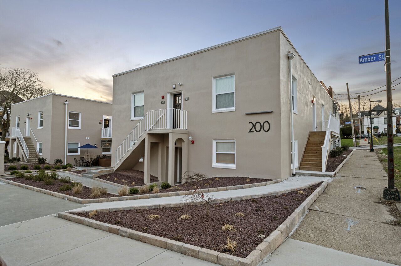 Un edificio de apartamentos de dos pisos, con fachada color beige, identificado con el número 200 en la calle Amber.
