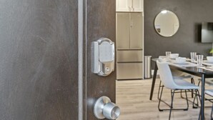 A modern kitchen with stainless steel appliances, a dining area with a table and chairs, and a large mirror on the wall.