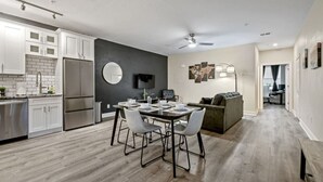 A modern kitchen with white cabinets, a built-in refrigerator, and a dining area with a table and chairs.