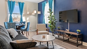 Un salon comprenant un canapé, des fauteuils, une table basse, un téléviseur et un coin repas avec des chaises et une table.