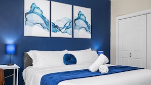 Une chambre d’hôtel avec un lit, une table de chevet, une lampe et des œuvres d’art accrochées au mur.