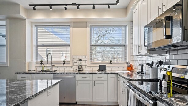A modern kitchen with white cabinets, a black countertop, and a stainless steel range hood. - Bright & Upscale|King Bed|Free Parking w/Workspace (Pittsburgh)