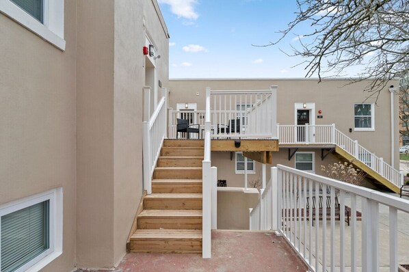 Un edificio de varios pisos con una escalera central, barandillas blancas y fachada color beige.