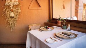 Une table à manger dressée avec des assiettes, des couverts et un objet décoratif.