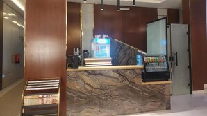 Una recepción con mostrador de mármol, cafetera y refrigerador.