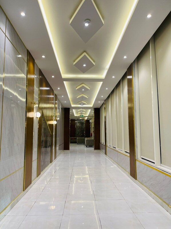 A corridor with a reflective floor, recessed lighting, and a symmetrical design.