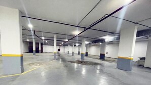 Un estacionamiento con varios niveles, pisos y pilares de concreto, con líneas amarillas y un diseño industrial moderno y limpio.