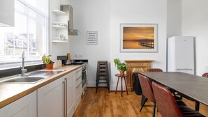 A modern kitchen with a wooden countertop, white cabinets, a built-in oven, and a large window with blinds. - Spacious apartment in London (London)