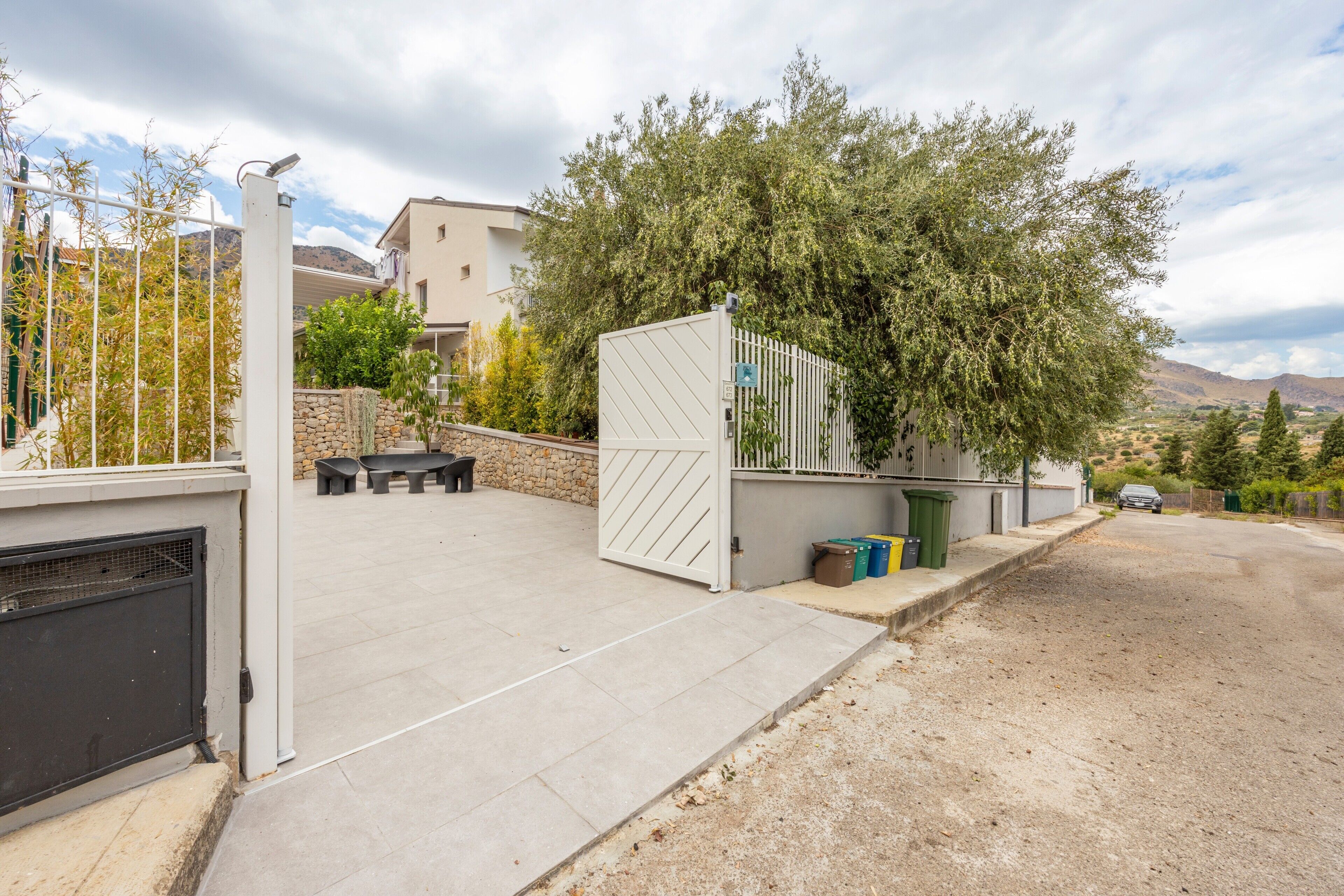 Un quartiere residenziale con ingresso carrabile, posti a sedere all'aperto e vista su dolci colline.