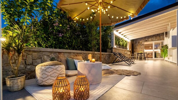 An outdoor patio with a stone wall, a round table, and a seating area with cushions. - 'Picahouse' Apartment with Sea View, Wi-Fi & Air Conditioning near Cefalù (Sant'Onofrio)