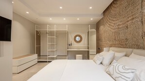 A modern bedroom with a large bed, a walk-in closet, a round mirror, and a textured wall. - 'Picahouse' Apartment with Sea View, Wi-Fi & Air Conditioning near Cefalù (Sant'Onofrio)