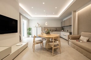 A modern living room with a flat-screen TV, a round dining table, and a sofa.