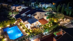 An aerial view of a residential area with a swimming pool, multiple houses, and well-lit outdoor areas. - 'Picahouse' Apartment with Sea View, Wi-Fi & Air Conditioning near Cefalù (Sant'Onofrio)