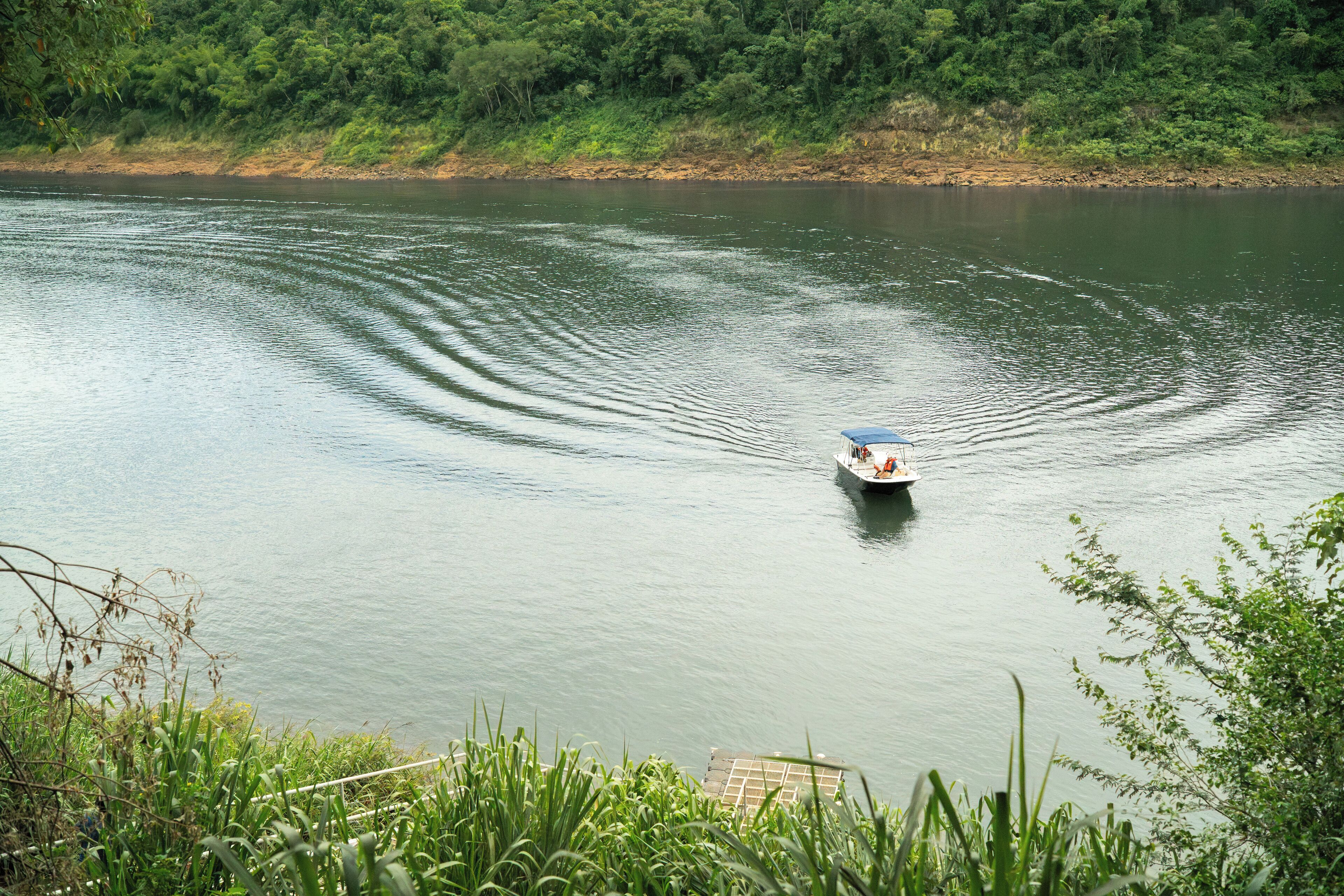 A boat on a calm river surrounded by lush greenery.