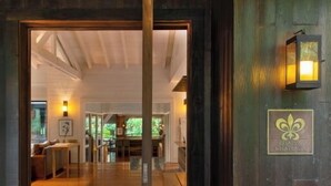 Una puerta de madera con un cartel que dice "RELAIS DE CHATEAUX" da acceso a una habitación amplia con piso de madera y un banco.