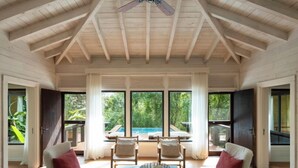 Una habitación amplia con techo alto, vigas de madera, ventanas grandes y ventilador de techo.