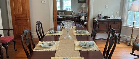 A dining room with a wooden table set for six, surrounded by chairs.