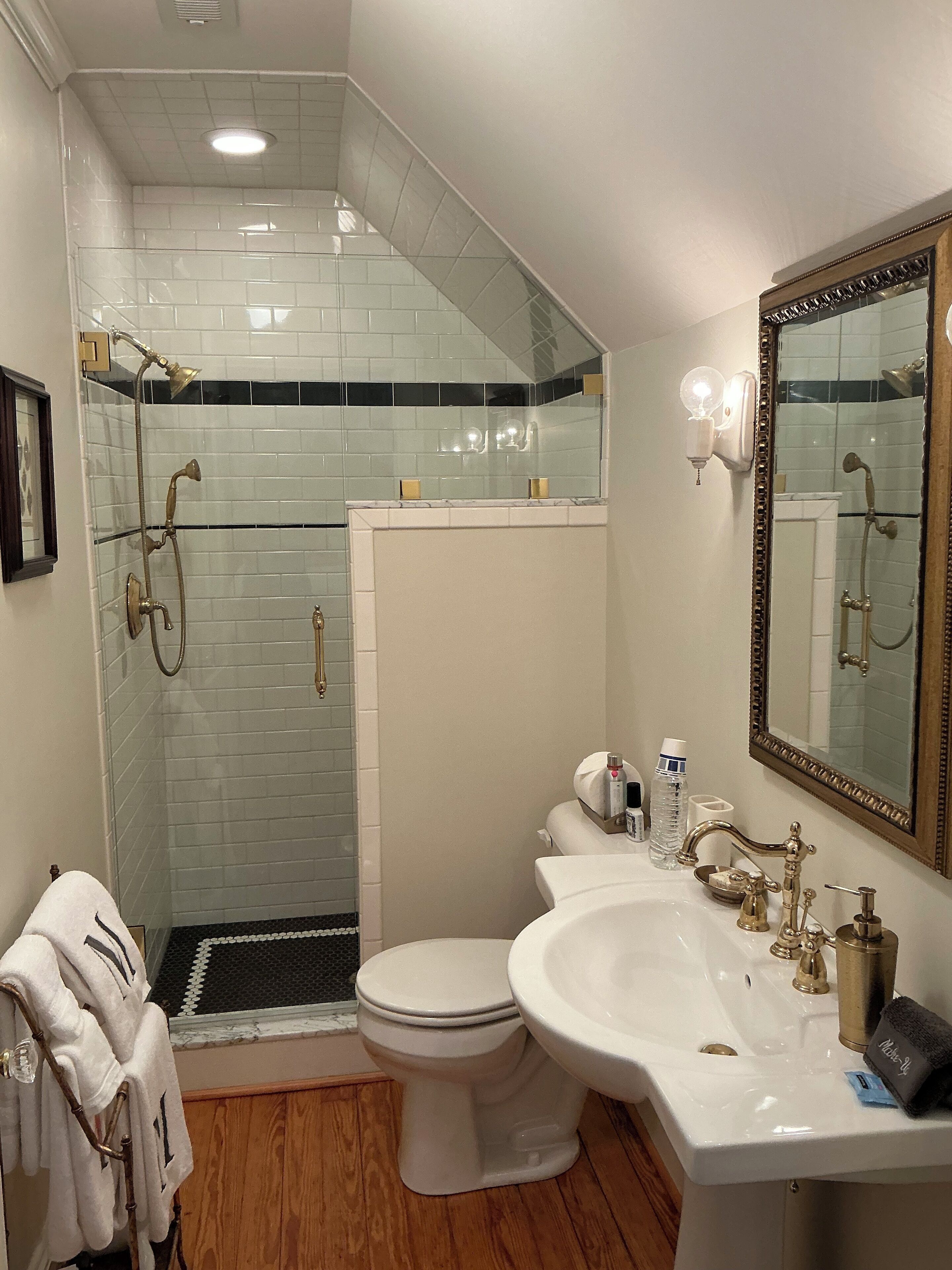 A bathroom with a shower, toilet, sink, and a large mirror.