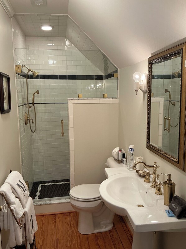 A bathroom with a shower, toilet, sink, and a large mirror. - Magnolia House Bed & Breakfast (Oriental)