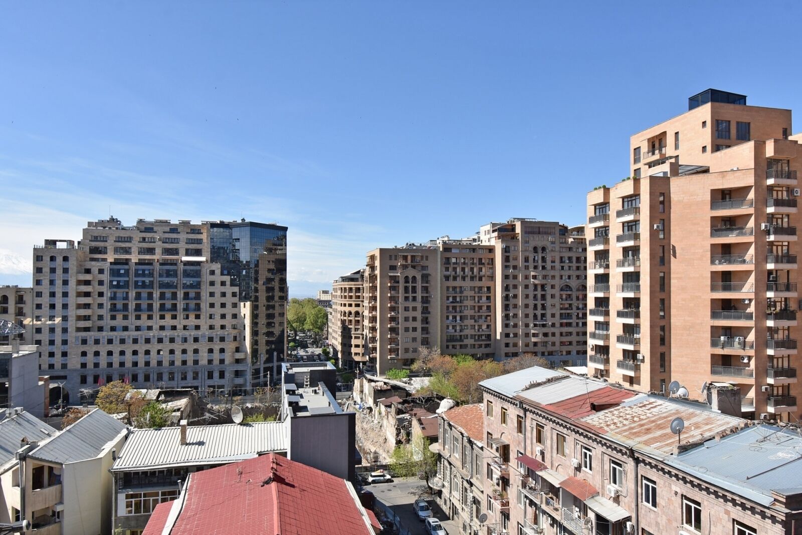 Une vue urbaine avec de hauts immeubles, dont un bâtiment moderne en verre et plusieurs structures plus anciennes en briques.