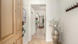 A hallway with a large vase of flowers, a coat rack, and a door with a picture frame.