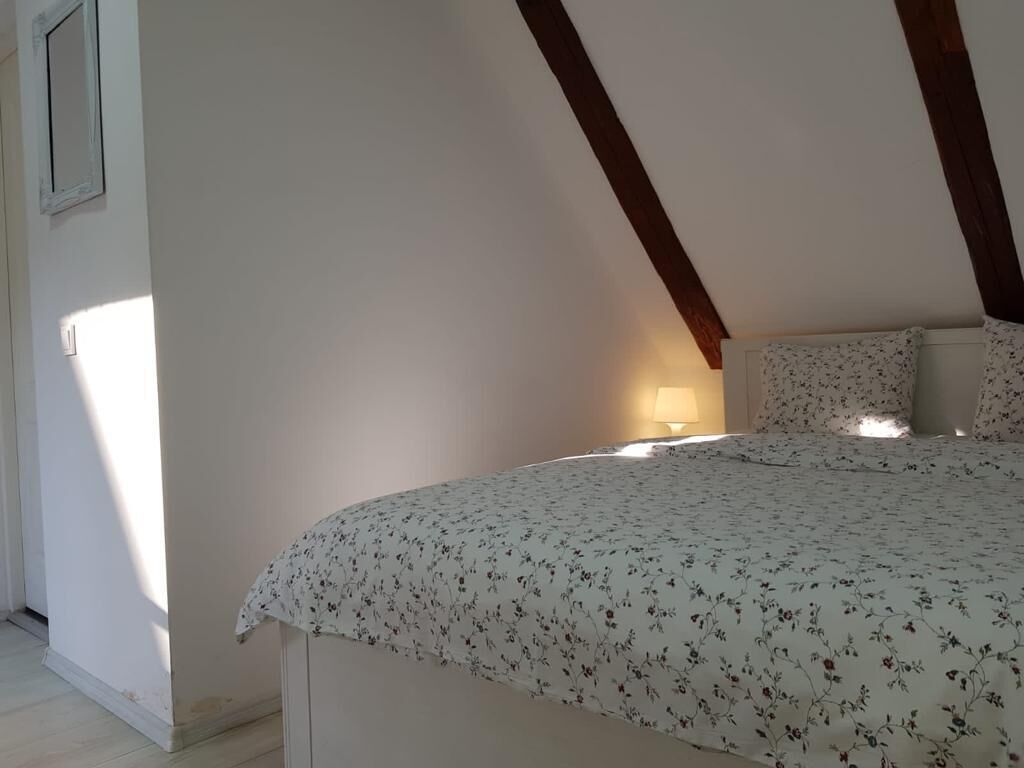 A bedroom with a bed, a nightstand, and a lamp.