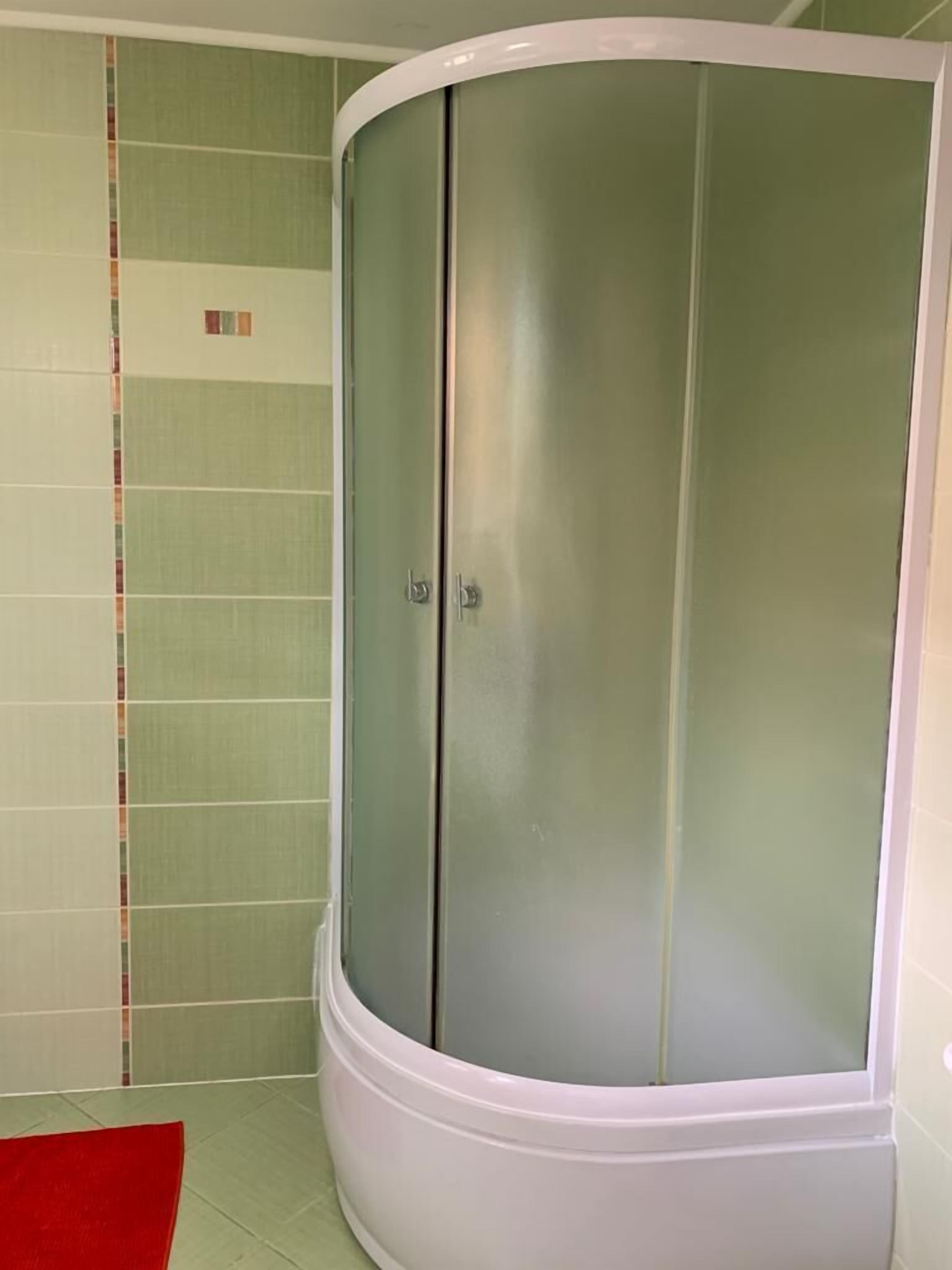 A room with a curved white wardrobe, green patterned walls, and a red rug.