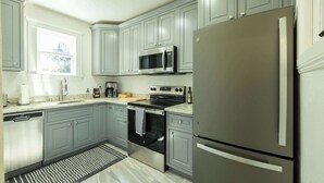 A modern kitchen with grey cabinets, stainless steel appliances, and a window providing natural light. - Beautiful Turn of the Century Home with Pet Friendly Yard (Martinez)
