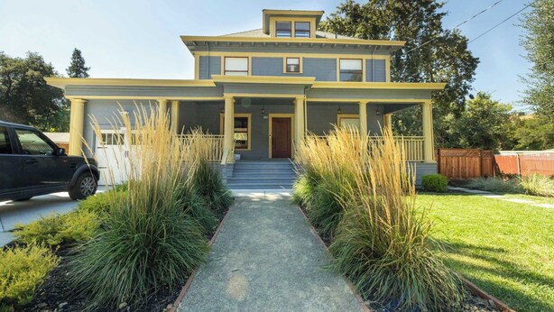 A two-story house with a front porch, a driveway, and a lawn. - Beautiful Turn of the Century Home with Pet Friendly Yard (Martinez)